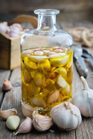 Garlic aromatic flavored oil or infusion bottle and garlic cloves. の写真素材