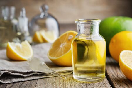 Bottle of citrus lemon essential oil and citrus fruits on table.の写真素材