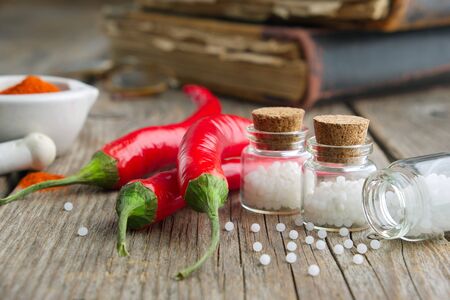 Red chili pepper and bottles of homeopathic globules of Capsicum. Homeopathy medicine.の写真素材