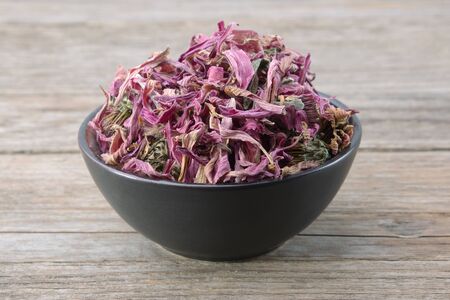Healthy echinacea flowers in black ceramic bowl on wooden table. Herbal medicine. の写真素材