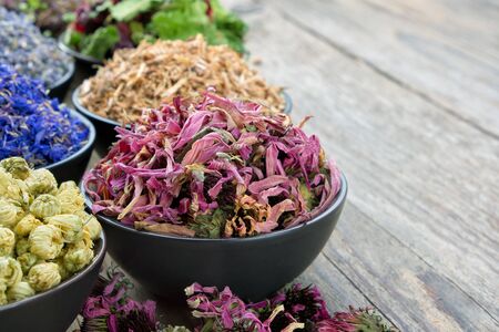 Bowls of dry medicinal herbs: coneflowers, cornflowers, daisies, lavender, oak bark. Healing herbs assortment. Copy space for text. Herbal medicine. の写真素材