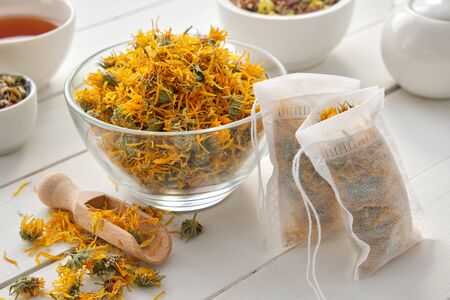 Bowl of dry marigold flowers, tea bags with dry Calendula plants.の写真素材