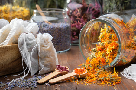 Filter tea bags filled with medicinal herbs. Glass jar of dry calendula flowers for making herbal tea, jars of various healthy herbs on table. Alternative medicine.medicine.の写真素材
