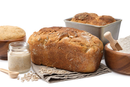 Homemade sourdough bread, natural leaven for bread in a glass jar, wooden bowl of dough and bowl of flour on white.の写真素材