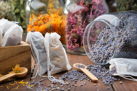 Filter tea bags filled with medicinal herbs. Glass jar of dry lavender flowers for making herbal tea, jars of various healthy herbs on background. Alternative medicine.の写真素材