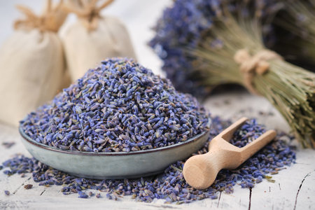 Blue plate of dried lavender. Wooden scoop of dry lavender flowers. Lavender bouquet and sachets on background.の写真素材