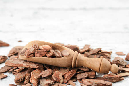 Pine bark and rustic wooden scoop on white wooden board.の写真素材
