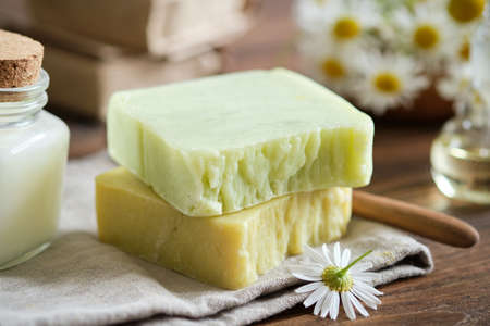 Homemade soap bars and daisy flowers. Bars of organic soap on table.
