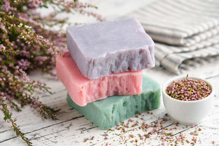 Homemade natural soap bars and heather flowers on white table. Bars of organic soap.