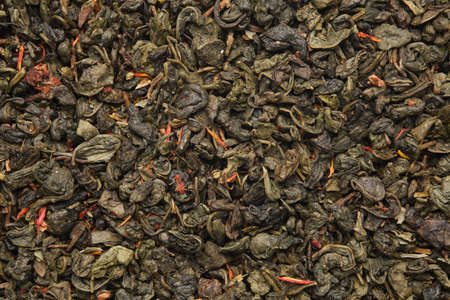 Green gunpowder tea texture. Dry green tea leaves background. Green tea with safflower flower petals.の写真素材