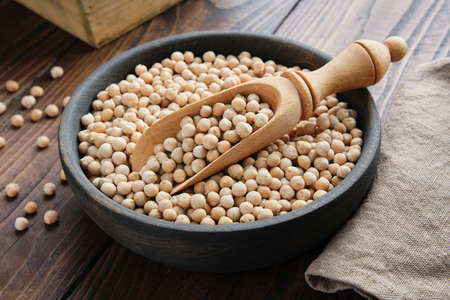 Raw chickpeas in bowl. Chickpeas in bowl and scoop on wooden table.の写真素材