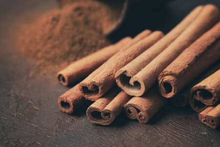 Aromatic cinnamon sticks and pile of sprinkled ground cinnamon on background. Selective focus.の写真素材