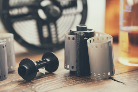 Photo film rolls and cassette, photographic equipment - developing tank with its film reels and chemical reagents on background.の写真素材