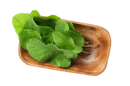 Wooden bowl of green Burdock leaves, isolated on white. Top view.の写真素材
