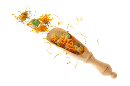 Wooden scoop of dried calendula flowers, isolated on white background. Petals of calendula flowers for making healthy herbal tea. top view.の写真素材