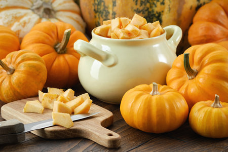 Chopped pumpkin pulp on a cutting board. Saucepan filled with chopped pumpkin prepared for cookingの写真素材