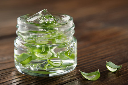 Glass jar of aloe vera gel, slice of aloe leaves on a wooden board. natural cosmetic and medicinal remedy.の写真素材