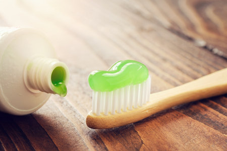 Eco friendly wooden bamboo toothbrush with toothpaste and tube of herbal toothpaste closeup.の写真素材