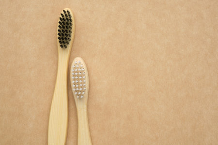 A pair of eco-friendly wooden bamboo toothbrushes. living together. love concept. A conceptual of a couple toothbrushes in love on brown kraft paper background. Top view, flat lay.の写真素材