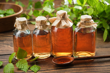 Bottles of birch essential oil, infusion or tincture. Birch syrup or coal tar oil bottles. Twigs of Birch tree with leaves. alternative herbal medicine.の写真素材