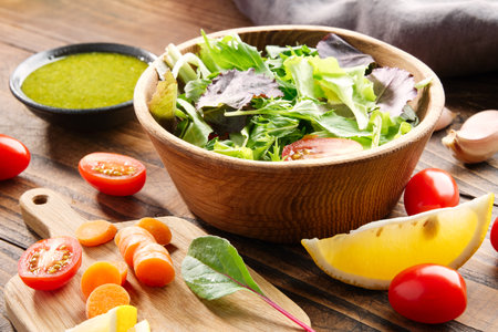 Vegetable salad in bowl and ingredients on wooden table.の写真素材