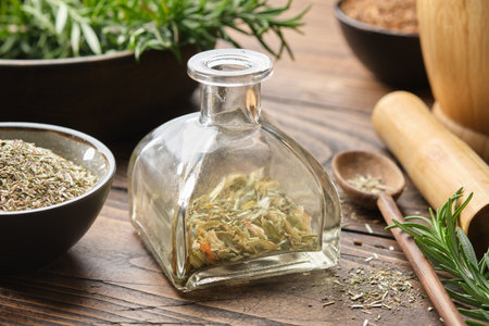 Bottle of dry herbs for making healing infusion or tincture. Bowls of medicinal plants and wooden mortar on background. Alternative herbal medicine.の写真素材