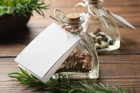 Bottle of healthy herbs with white empty label for you text. Glass bottle of dry medicinal herbs for making healing infusion or tincture. Rosemary medicinal plants on background.の写真素材