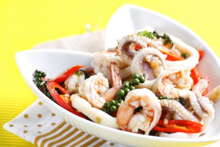 Sizzling spicy fried squid and shrimp on fabric in yellow background の写真素材