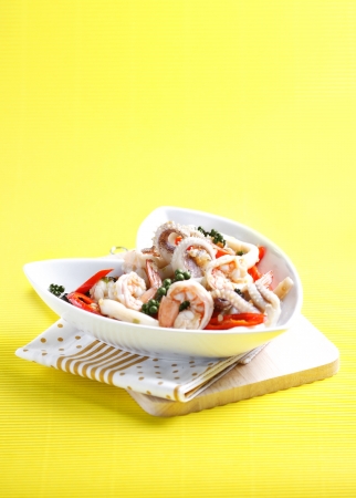 Sizzling spicy fried squid and shrimp on fabric in yellow background の写真素材