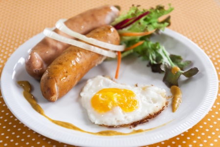 Sausage and fried egg on white dish in polka dots background の写真素材