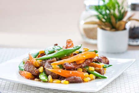 Stir-fried mixed vegetables with pork in square dish on white mat background の写真素材