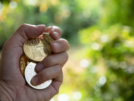 hand holding coin with nature bokeh background and copy space, cryptocurrency money exchange investment concept.の写真素材