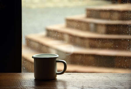 Coffee cup on wooden table near the window in cafe backgroundの写真素材