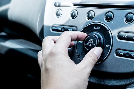 Close up driver hand adjust audio button in the car