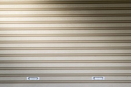 illuminated grunge metallic roller auto shutter door with light from cornerの写真素材