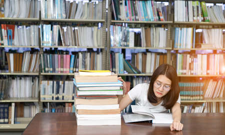 Young Girl Student with Glasses Reading book Overlap Serious, Hard Exam, Quiz, Test Sleeping headache worry in Classroom Education Library University Knowledge centerの写真素材