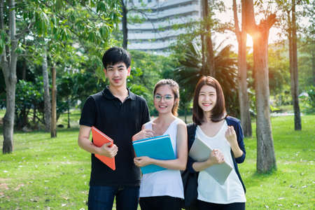 Young Student Asian Group Teenager with school folders on grass at university campus collegeの写真素材