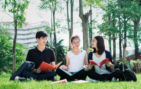 Young Student Asian Group Teenager with school folders on grass at university campus collegeの写真素材