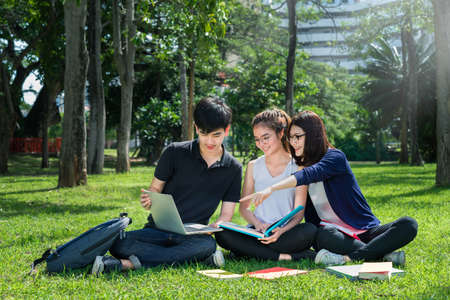 Young Student Asian Group Teenager with school folders on grass at university campus collegeの写真素材