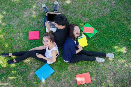 Young Students Group Smiling with Folders Book and Laptop computer Smiling on Grass in Educationの写真素材