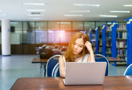 Young Student Girl Homework with Laptop Computer Serious, Hard Exam in Classroom Education Libraryの写真素材