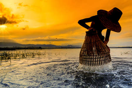 Children Fisherman boy with catching fish and fisherman throwing nets and girl on boat on lake river thailandの写真素材