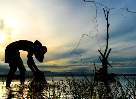 Children Fisherman boy with catching fish and fisherman throwing nets and girl on boat on lake river thailandの写真素材