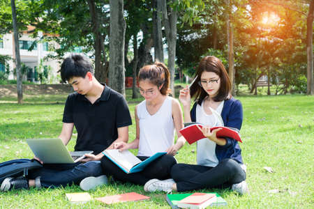 Young Student Asian Group Teenager with school folders on grass at university campus collegeの写真素材