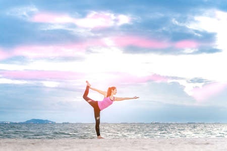 Young woman yoga exercise posting on the beach in summerの写真素材