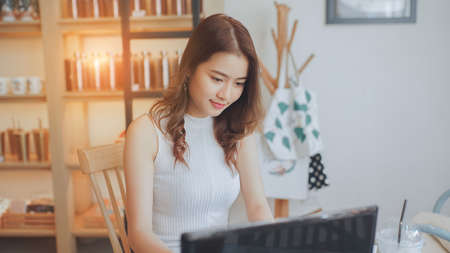 Asian young woman happiness sitting working with laptop smile in cafe shop with coffee brake on vacation holiday rest and relaxの写真素材