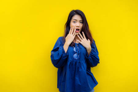 Young girl asian shocked product sale with glasses  on yellow backgrond studioの写真素材