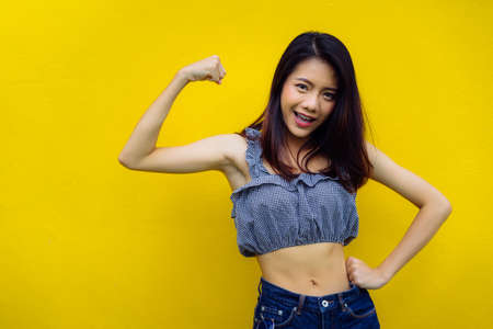 Asian young girl strong fitness workout concept on yellow background studioの写真素材