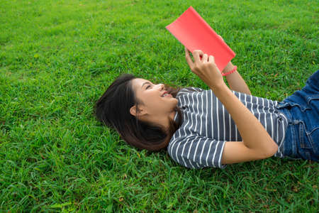 Asian young girl relax and reading book on park grass in summer
