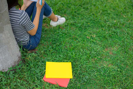 Asian young girl reading book on park in holidaysの写真素材